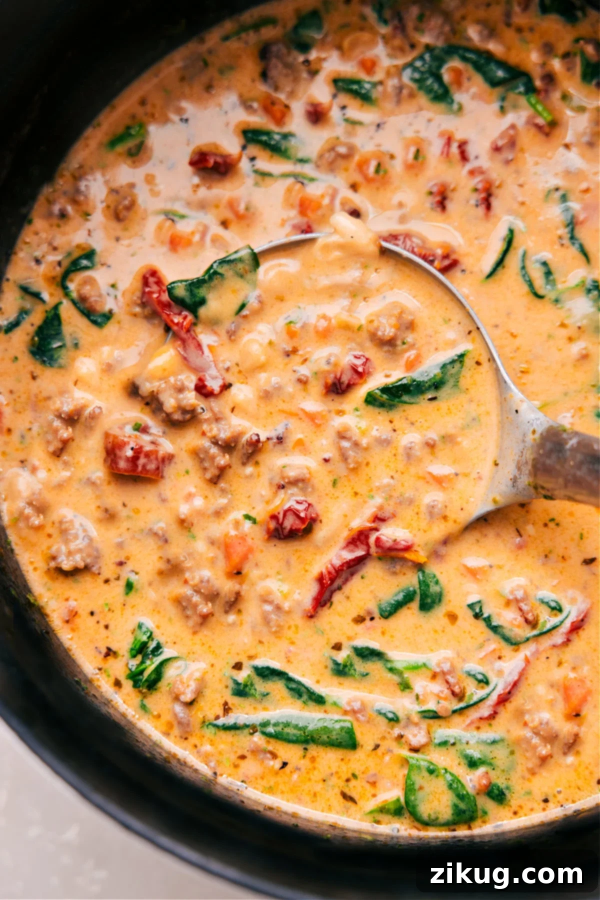 The Best Tuscan Soup Recipe for Ultimate Comfort A rich, creamy Tuscan Soup in a large pot, with a ladle scooping up a generous portion, showcasing pieces of sausage, beans, and spinach.