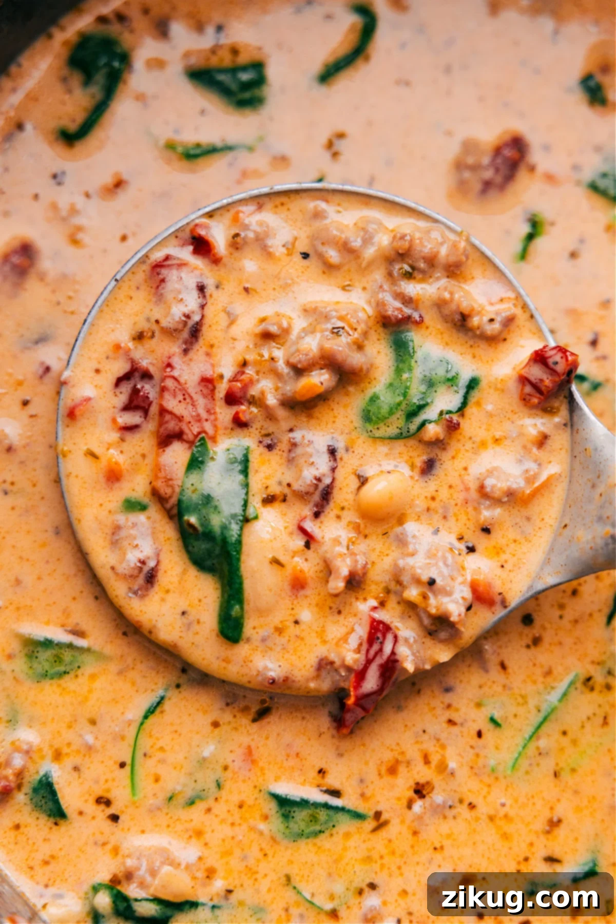 Scoop Out Some Tuscan Soup And Enjoy Your Hearty Meal A ladle scooping out a generous portion of the best creamy Tuscan soup from a large pot, showing all the delicious ingredients like sausage, beans, and spinach.