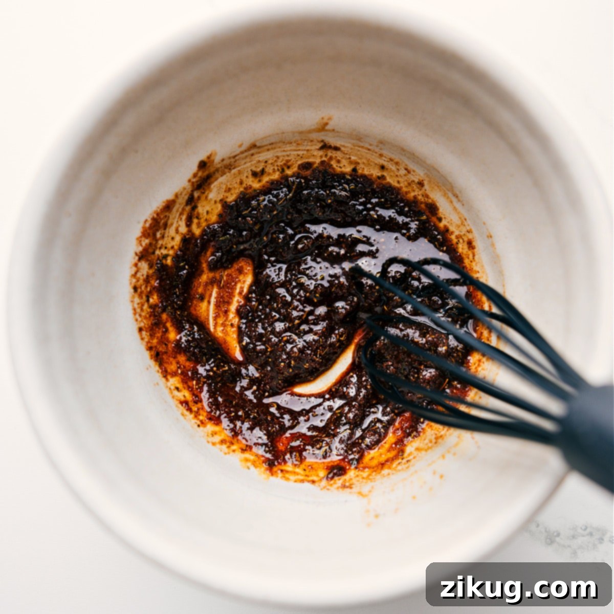 Crafting The Best Jerk Chicken Rub Recipe at Home Jerk Chicken marinade ingredients including various spices, oil, and soy sauce being whisked together in a bowl to create the perfect rub.