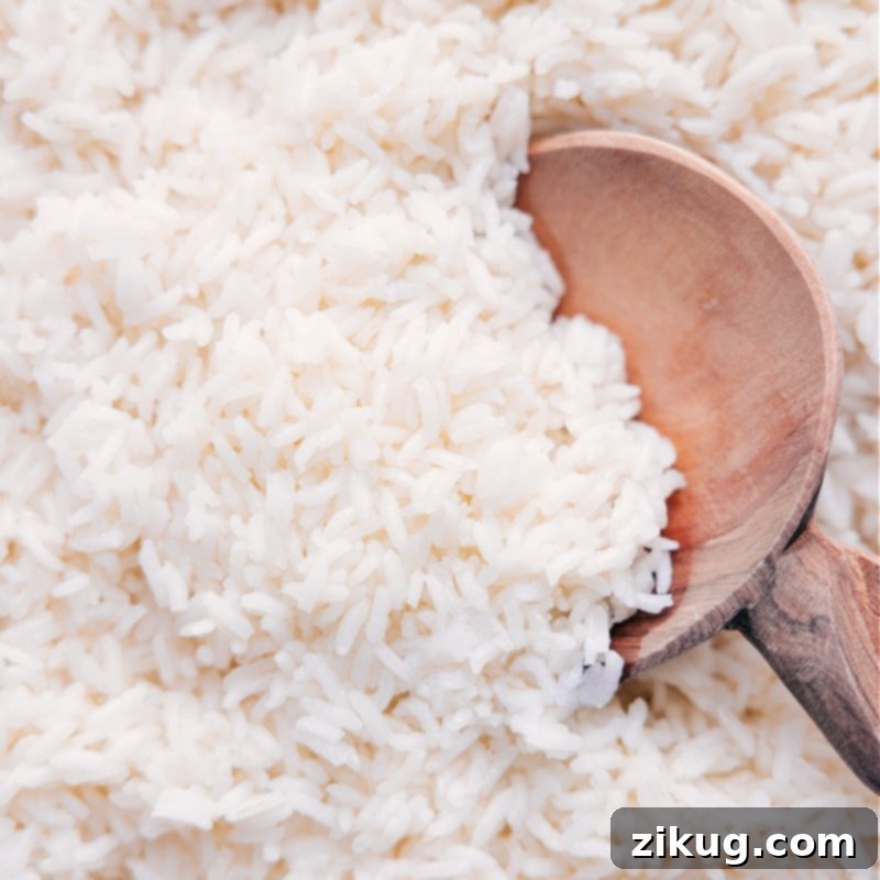 A perfectly cooked bowl of fluffy white rice, ready to be served, garnished with fresh green herbs, showcasing its pristine texture
