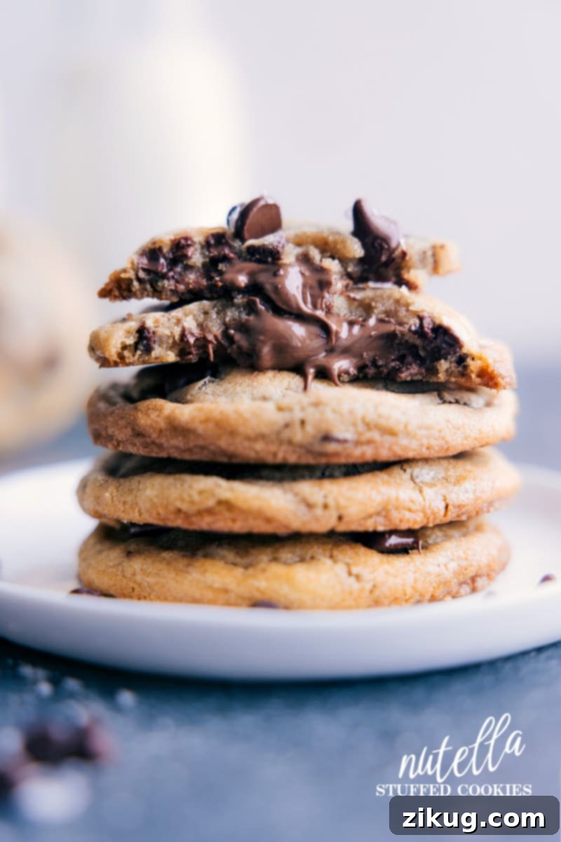 Indulge in the ultimate Nutella-Stuffed Chocolate-Chip Cookies with a crunchy exterior, chewy interior, two chocolate chip types, and a gooey Nutella surprise. Recipe via chelseasmessyapron #dessert #best #quick #easy #simple #familyfriendly #kidfriendly #comfortfood #nutellastuffed #chocolatechip #cookies Irresistible Nutella-Stuffed Chocolate Chip Cookies with a gooey center