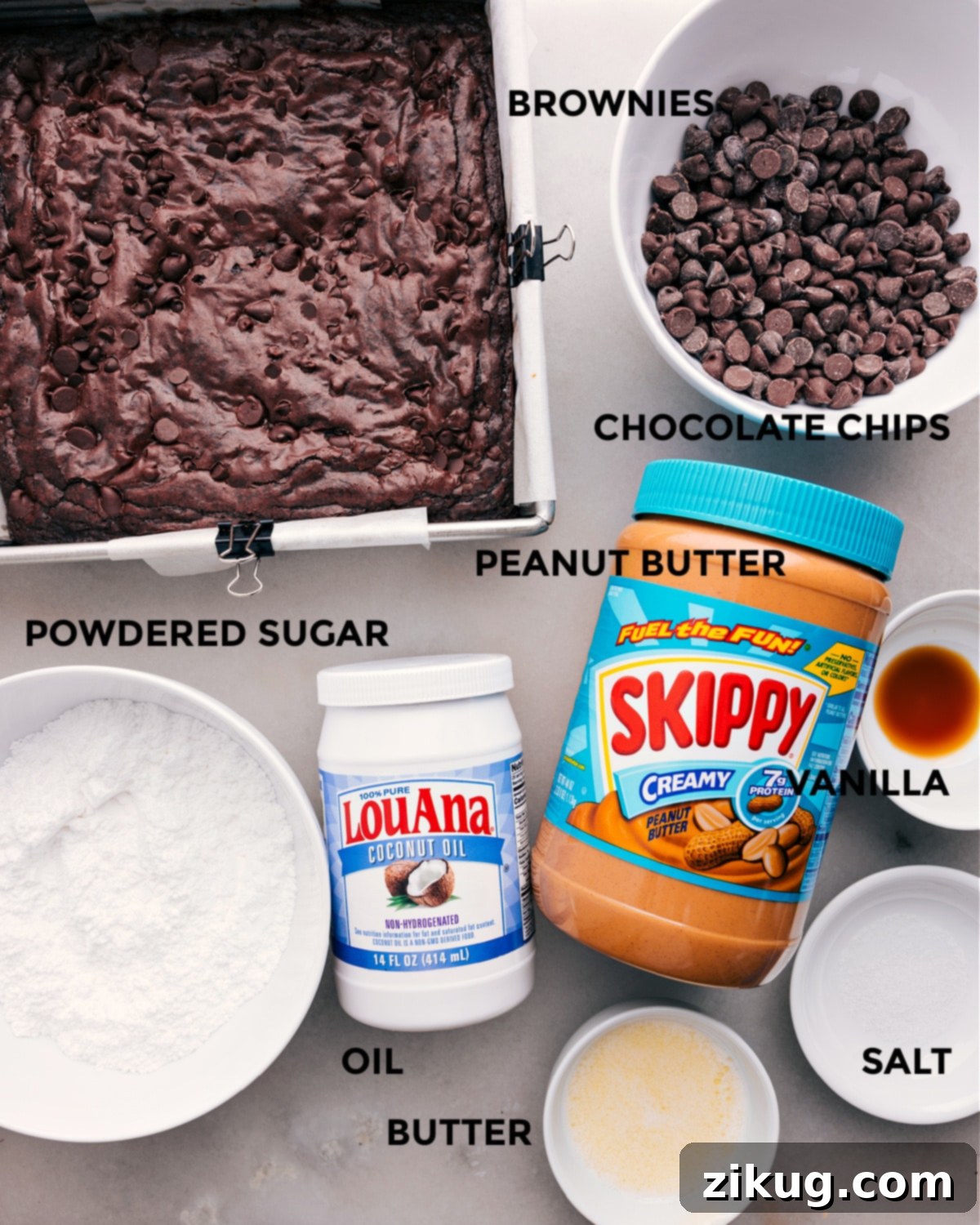 A selection of ingredients for Buckeye Brownies, including brownie mix, chocolate chips, peanut butter, sugar, vanilla, oil, and butter.