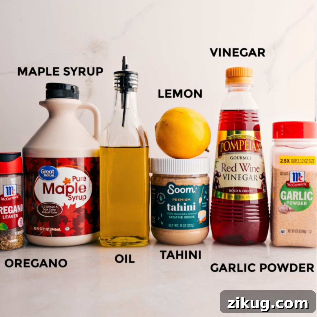 Ingredients for the grain bowl's lemon tahini dressing, including tahini, maple syrup, fresh lemons, olive oil, red wine vinegar, garlic powder, and oregano, neatly arranged for preparation.