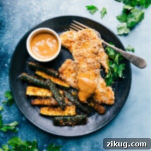 Delicious Sheet Pan Parmesan Chicken and Zucchini with a side of dipping sauce.
