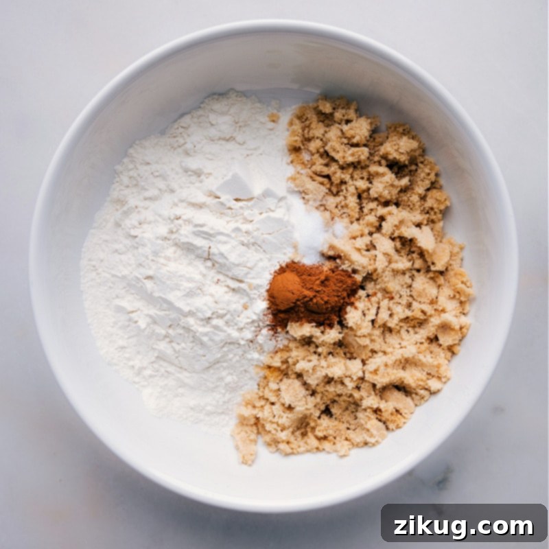 Process shot showing flour, brown sugar, and spices being added to a mixing bowl, an essential step in learning how to make streusel