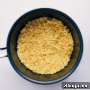 A beautifully presented bowl of fluffy couscous, garnished with fresh cilantro and vibrant golden raisins, making it an inviting and healthy side dish.