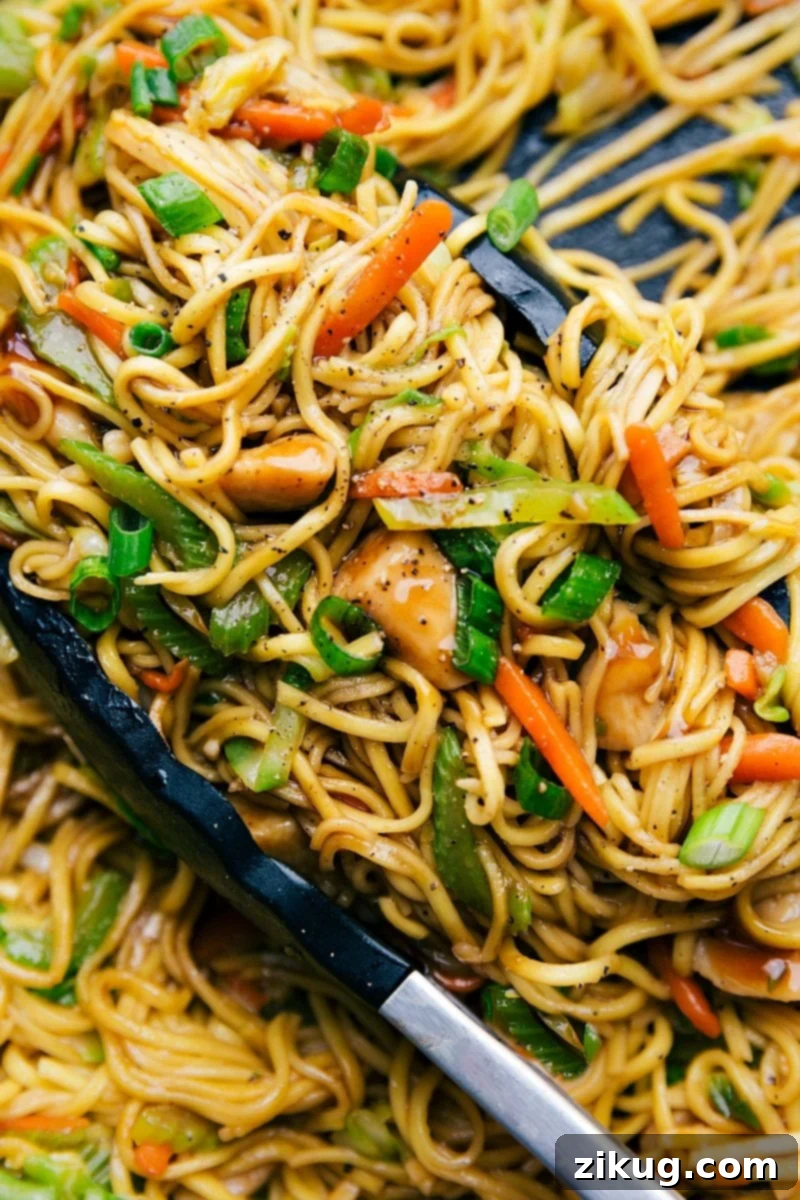 Chicken Chow Mein with Fresh Vegetables Chicken chow mein in a skillet with tongs, filled with fresh vegetables, perfectly cooked and seasoned.