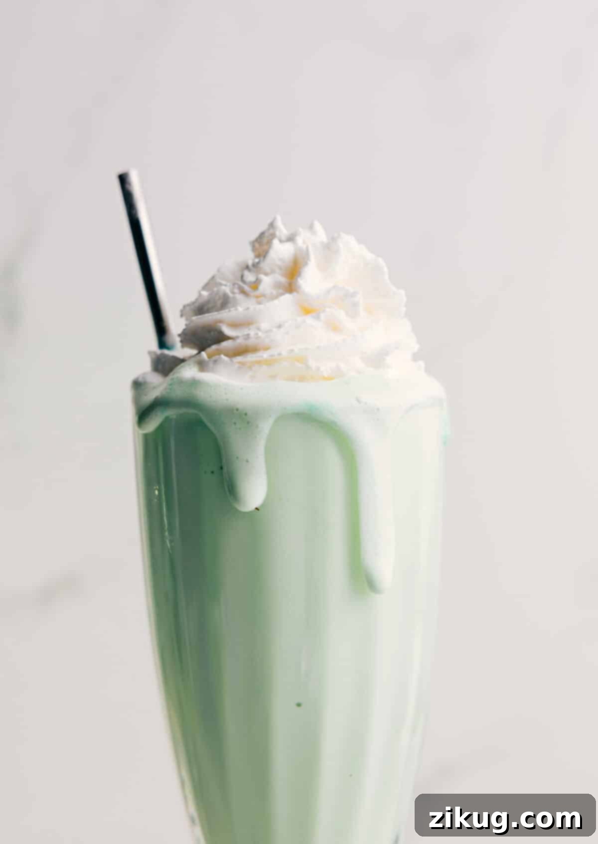 Thick And Creamy Homemade Shamrock Shake A vibrant green Shamrock Shake, thick with whipped cream and a cherry on top, served in a tall glass.