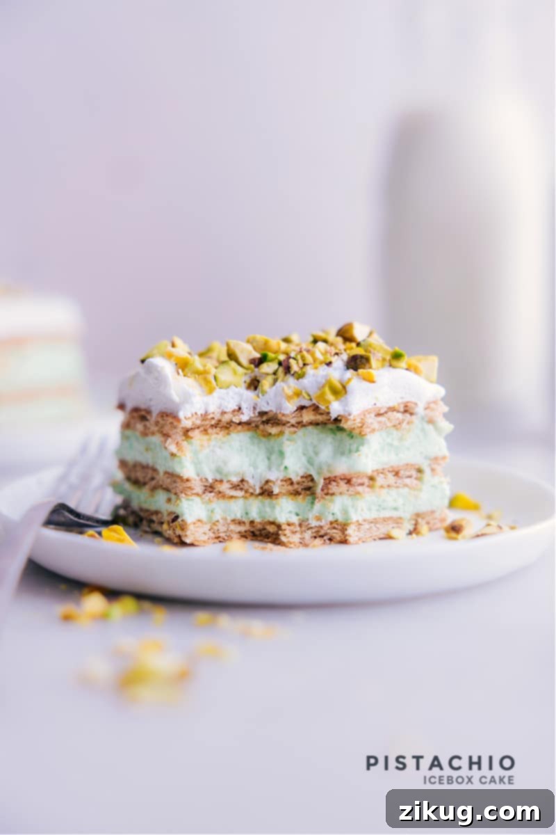 A beautifully presented Pistachio Icebox Cake slice, showcasing its distinct green layers of pudding and white whipped cream topping, garnished with chopped pistachios. The cake is soft, creamy, and ready to be enjoyed.