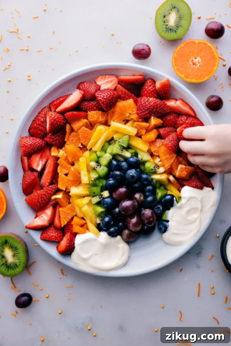 Overhead view of a vibrant Fruit Rainbow Tray with a creamy white dip, resembling clouds