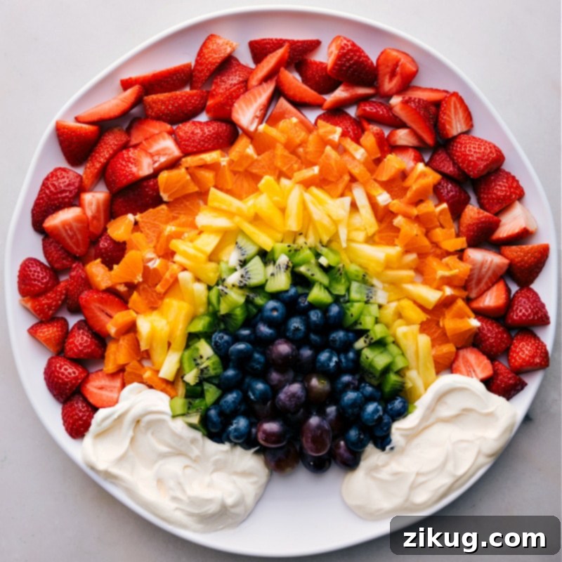 Overhead image of a beautifully arranged Rainbow Fruit Tray, ready for serving with a bowl of creamy dip