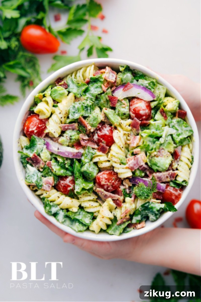 The Ultimate BLT Pasta Salad: Fresh, Flavorful, and Easy to Make Overhead image of a vibrant BLT Pasta Salad in a large serving bowl, showcasing crispy bacon bits, halved cherry tomatoes, green romaine, and creamy pasta coated in avocado dressing.