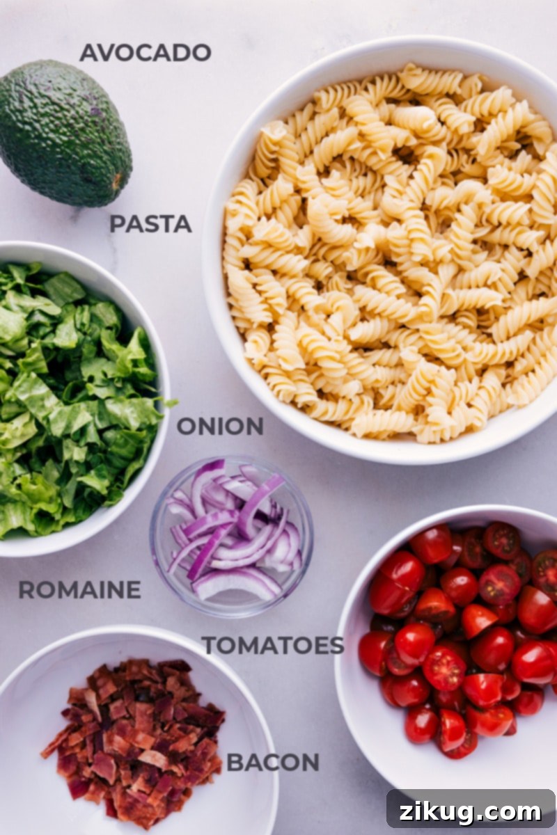 Fresh Ingredients for the Perfect BLT Pasta Salad A flat lay image displaying all the fresh ingredients for BLT Pasta Salad: rotini pasta, strips of raw bacon, cherry tomatoes, a head of romaine lettuce, red onion, ripe avocados, fresh dill, and bottles of buttermilk, mayonnaise, and lemons.