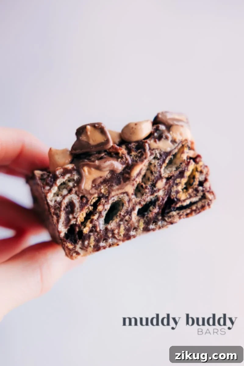 Close-up image of a square Muddy Buddy Bar, showcasing its chocolate, peanut butter, and powdered sugar coating with Chex cereal visible.