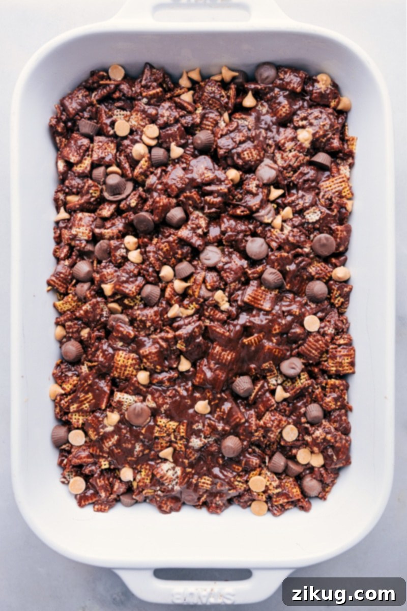 Overhead shot of the Muddy Buddy Bar mixture being gently pressed into a 9x13-inch baking pan, ready to set.