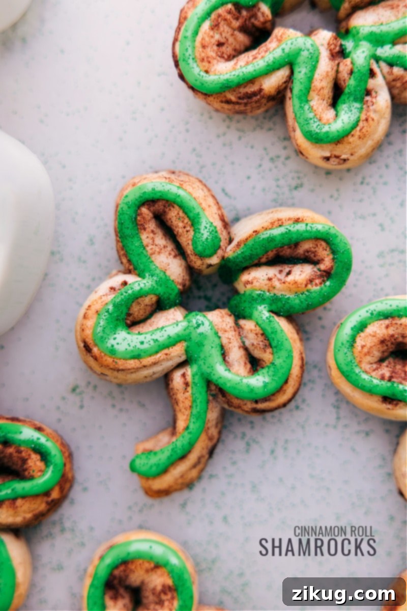 St. Patrick's Day is just around the corner! These adorable treats are not only festive and fun, but they're also incredibly easy to make. With just a can of refrigerated cinnamon rolls and some green food coloring, you can transform a classic breakfast pastry into a holiday masterpiece that kids and adults alike will love! Recipe via ChelseasMessyApron.com #cinnamonrolls #breakfast #shamrock #Stpatricksday #holiday #treat Overhead view of several perfectly iced Shamrock Cinnamon Rolls, arranged festively on a plate.