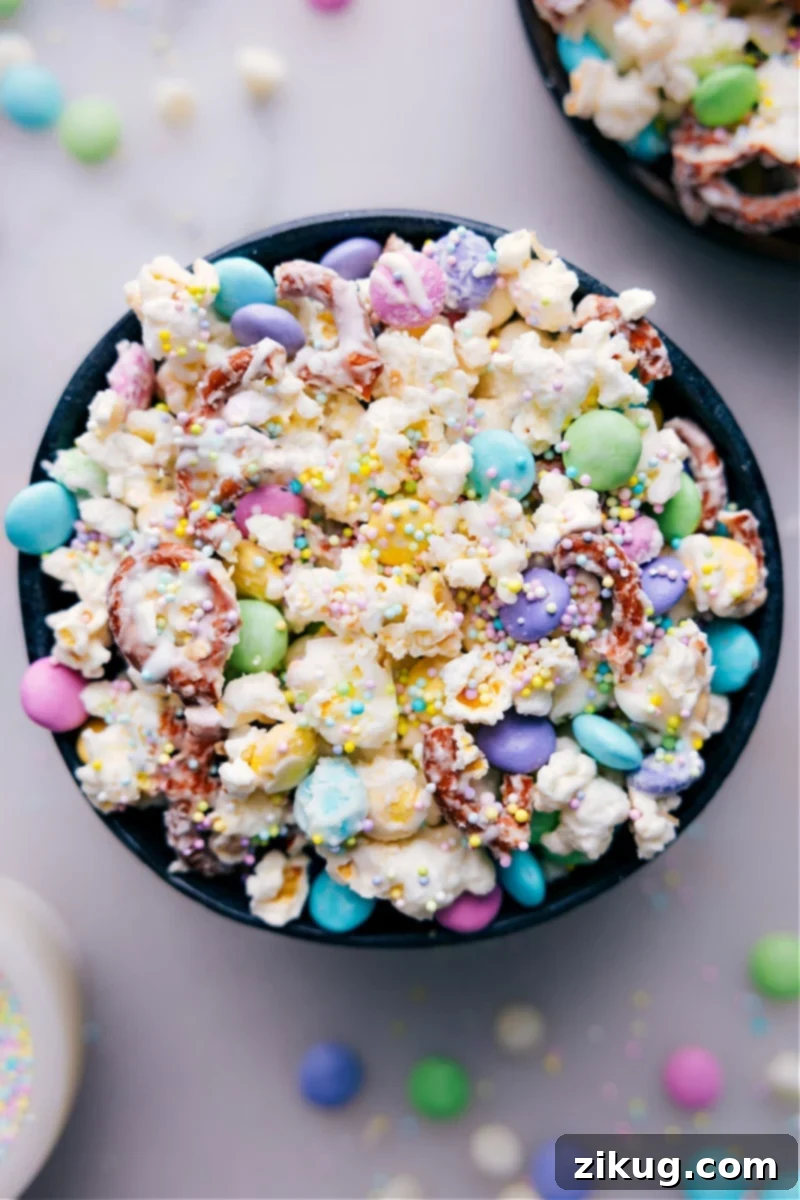 Overhead shot of freshly made Easter Popcorn, a vibrant mix of white chocolate-coated popcorn, pretzels, and colorful Spring M&M's, spread on a baking sheet, ready to be enjoyed.