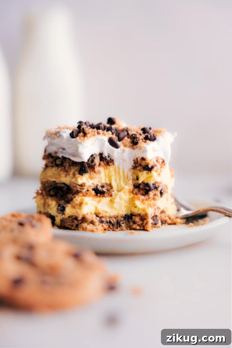 Looking for an impressive dessert that won't take hours in the kitchen? Then, you've got to try this Chocolate Chip Cookie Icebox Cake! Recipe via chelseasmessyapron #dessert #best #quick #easy #simple #familyfriendly #kidfriendly #chocolatechip #cookie #iceboxcake Close-up image of a slice of Chocolate Chip Cookie Icebox Cake on a plate, showing a bite taken out, highlighting the rich, creamy layers and softened cookie texture.