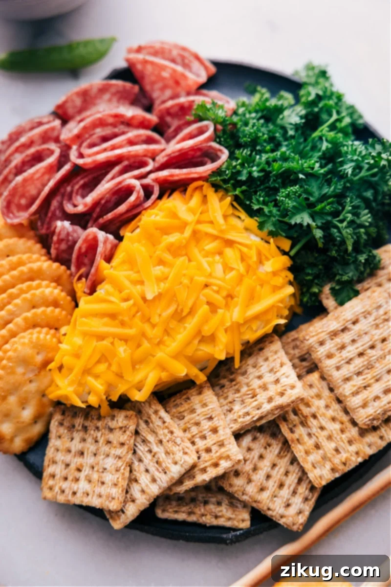 A vibrant Carrot Cheeseball, perfect for Easter and spring, surrounded by a variety of dippers like crackers, cold cuts, and fresh vegetables. Overhead image of the Carrot Cheeseball with crackers and vegetables