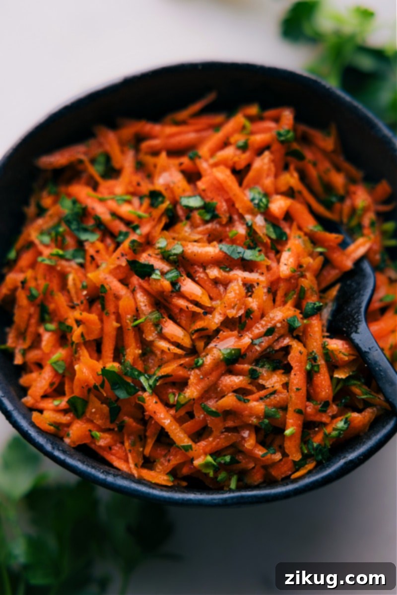 A perfectly prepared French Carrot Salad, glistening with its zesty lemon-honey-Dijon dressing, ready to be served. Up-close overhead image of the prepared French Carrot Salad in a bowl, ready to be enjoyed.