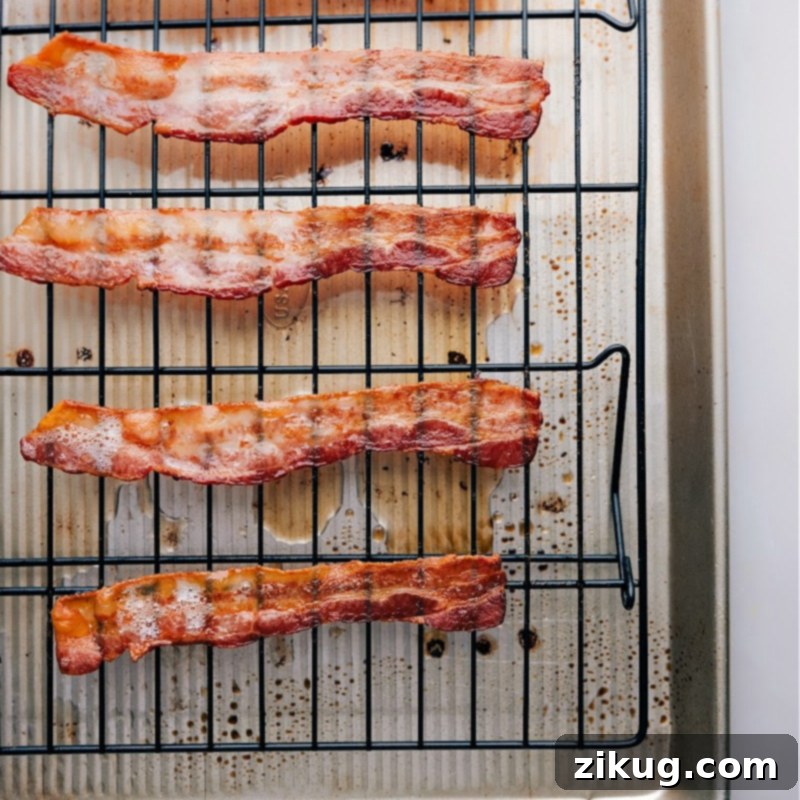 Freshly baked crispy bacon removed from the oven, resting on paper towels to drain excess fat.