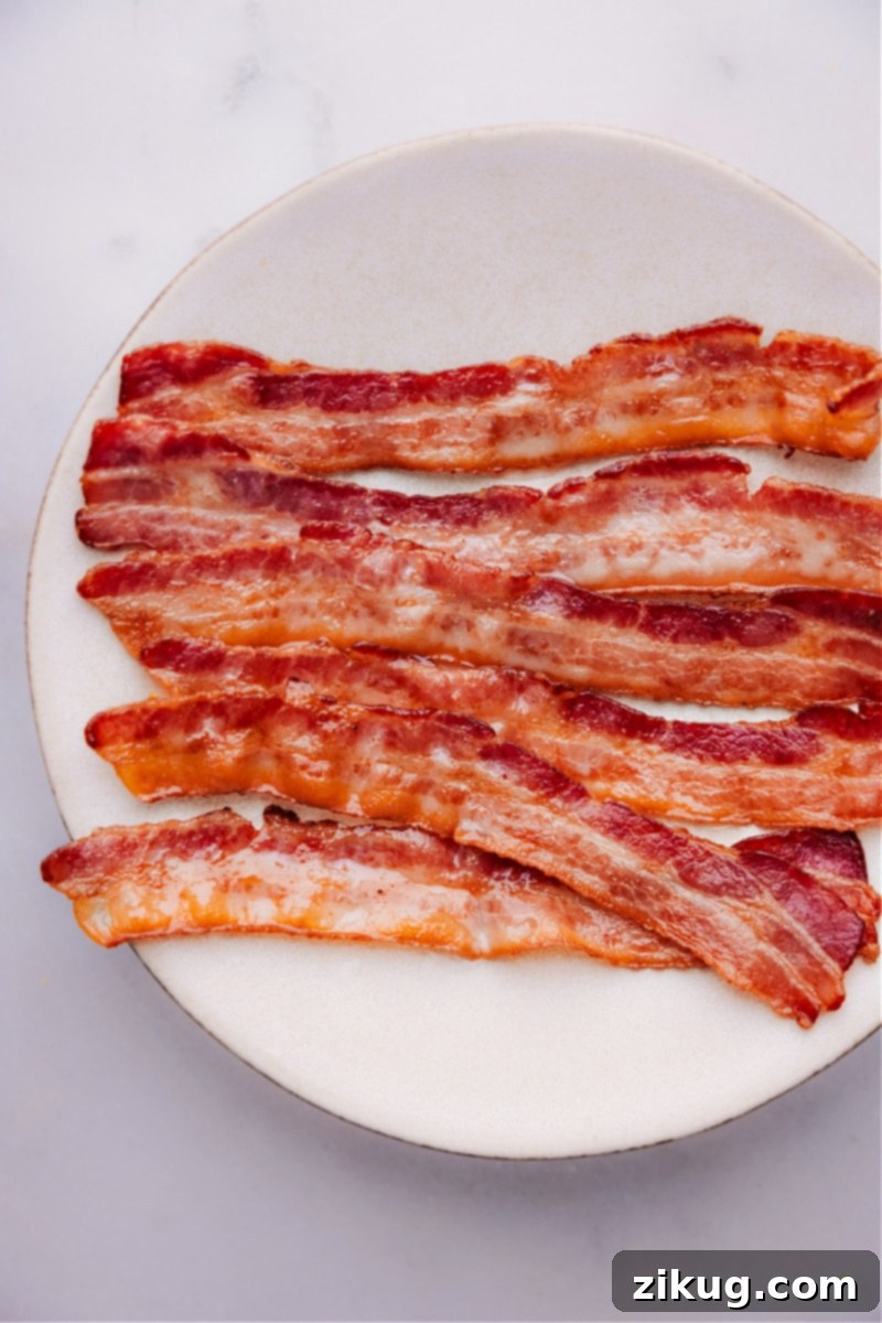 A breakfast plate featuring perfectly baked crispy bacon alongside scrambled eggs, ready to be enjoyed.