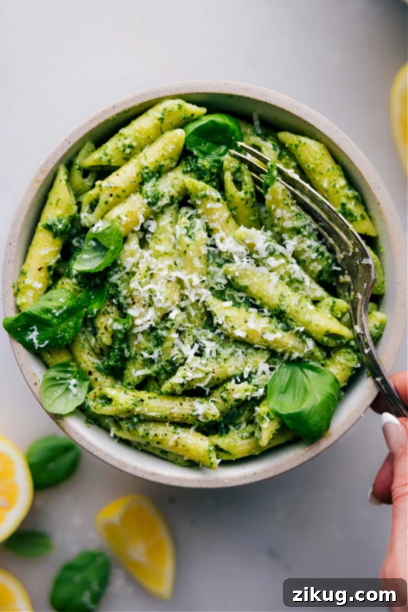 Discover the most delicious and easy Pesto Pasta recipe! Perfect for quick weeknight dinners, this dish is bursting with fresh basil flavor and comes together in less than 20 minutes. A truly family-friendly meal that tastes like it's from an Italian restaurant. #PestoPasta #EasyDinner #QuickRecipe #WeeknightMeal #FamilyFriendly Overhead image of freshly made Pesto Pasta in a rustic bowl, garnished with fresh basil leaves and grated Parmesan cheese.