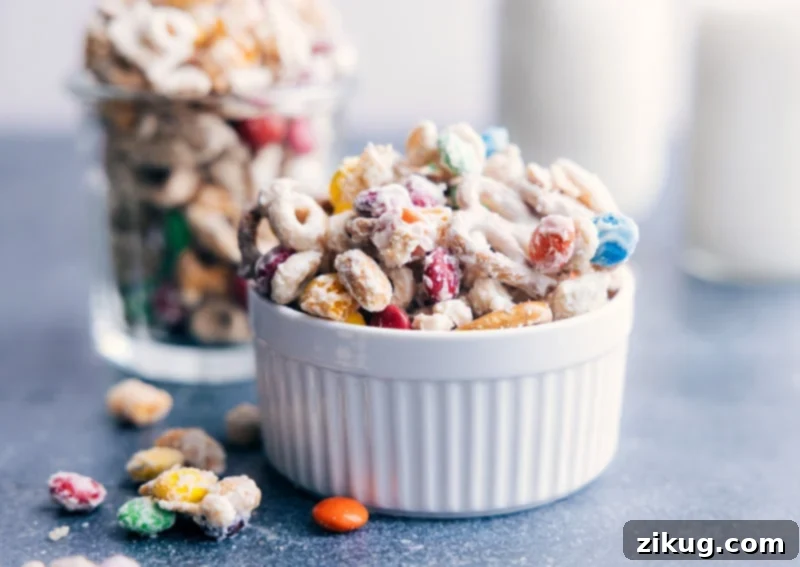 Enjoy a bowl of this irresistible White Chocolate Chex Mix: a perfect sweet and salty treat. A beautifully arranged bowl of White Chocolate Chex Mix, featuring a delightful blend of cereal, pretzels, peanuts, and M&M's, all coated in a luscious white chocolate glaze, ready to be enjoyed.