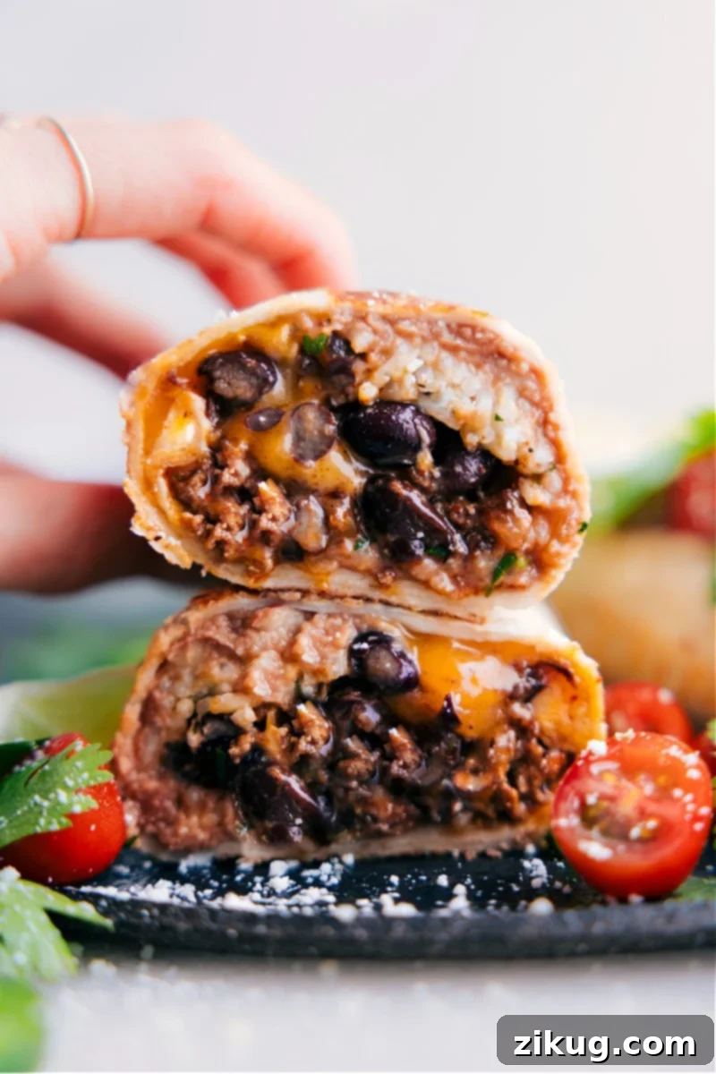 Image of the Beef Burrito Recipe cut in half, with the halves stacked on top of each other, showcasing the savory seasoned ground beef, zesty cilantro lime rice, creamy refried beans, and melted sharp cheddar cheese.