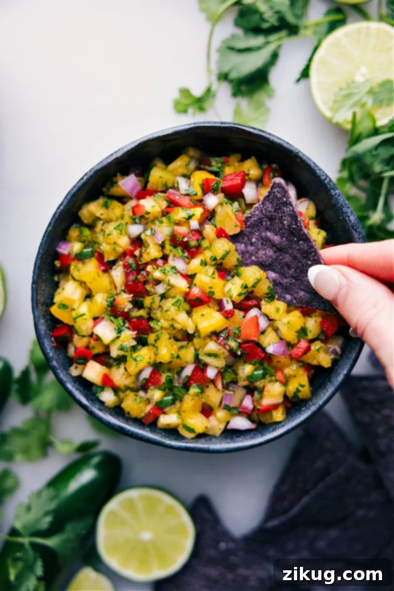 The Tastiest Pineapple Salsa: A Burst of Tropical Flavor A crisp tortilla chip dipping into a bowl of brightly colored homemade pineapple salsa, showcasing its fresh ingredients.