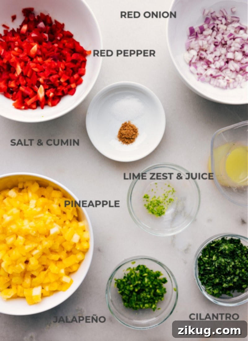 All The Fresh Ingredients You Need for Perfect Pineapple Salsa All the fresh ingredients laid out on a cutting board, ready for chopping: a whole pineapple, red onion, red bell pepper, jalapeño, fresh cilantro, limes, and small bowls of salt and cumin.