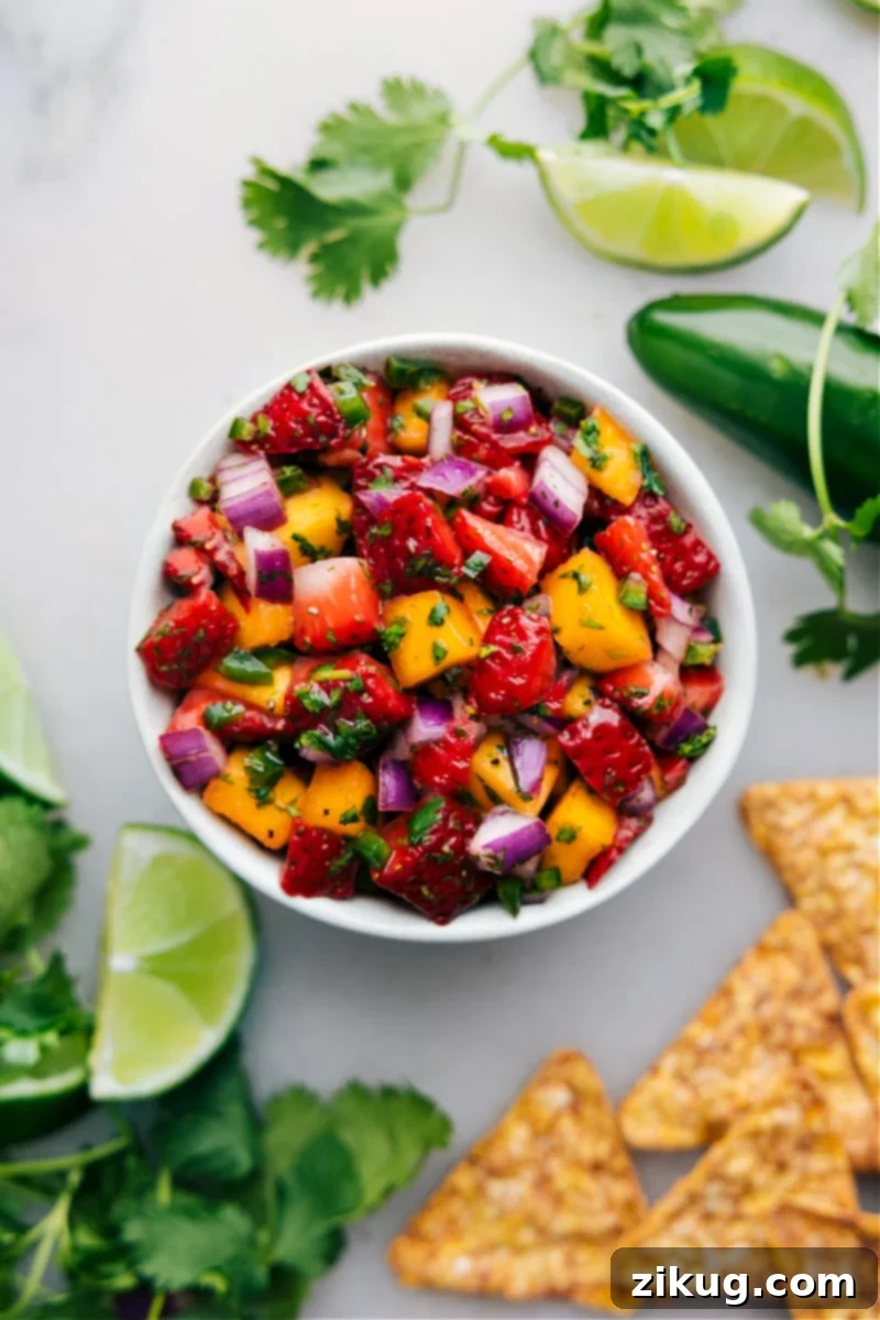 Quick And Easy Strawberry Mango Salsa Recipe A vibrant bowl of Strawberry Mango Salsa, generously garnished with freshly chopped cilantro, waiting to be enjoyed as a refreshing summer snack or appetizer.