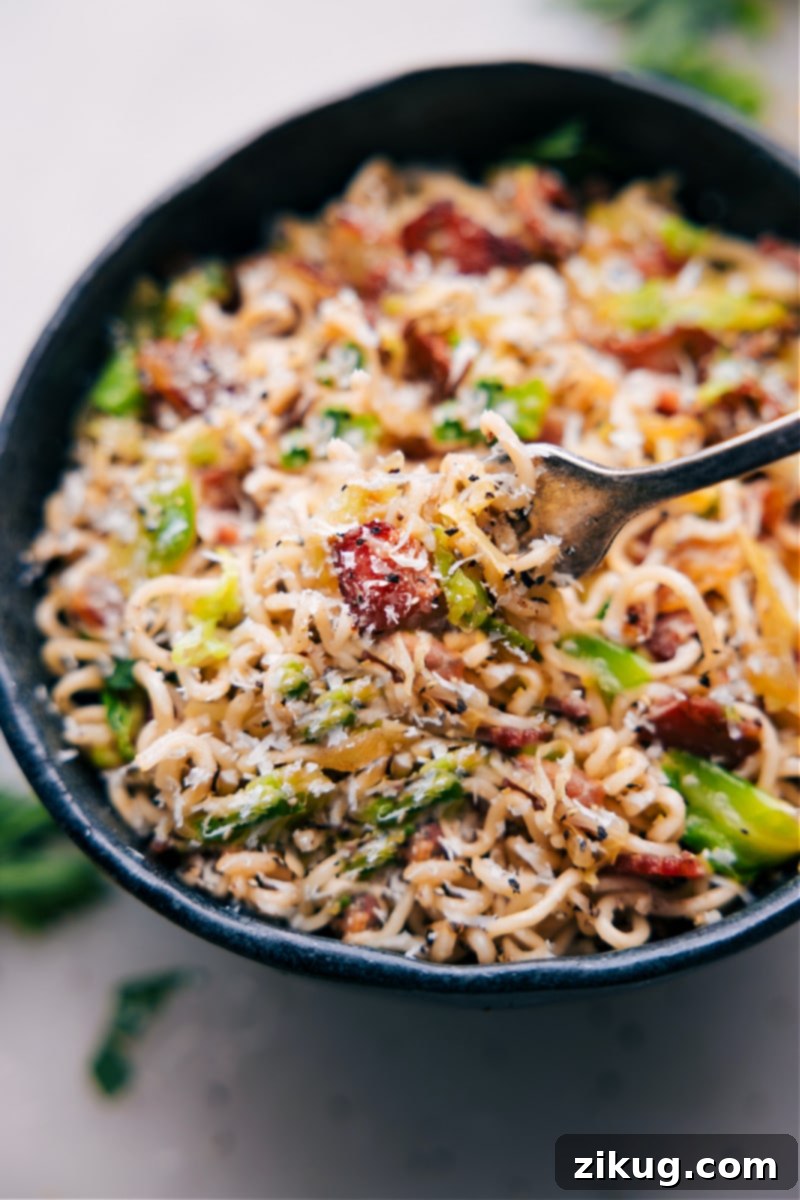 An appealing image of a fork lifting a generous serving of Fried Cabbage Ramen from a bowl, highlighting the perfectly coated noodles, crispy bacon, and tender cabbage.