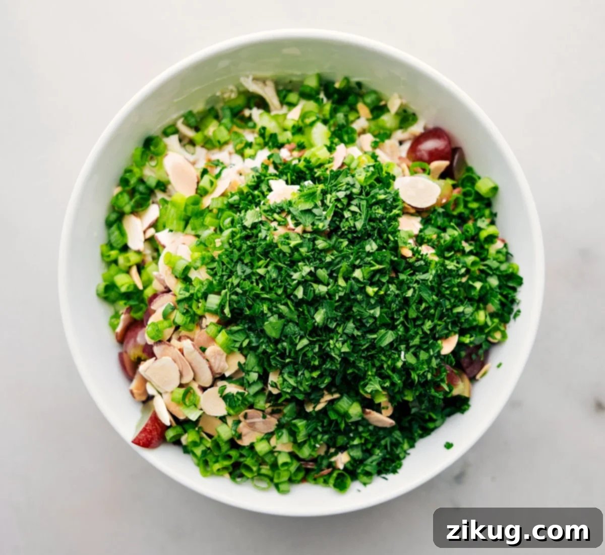 All the delicious ingredients being added to a large bowl to be tossed together for the healthy chicken salad.