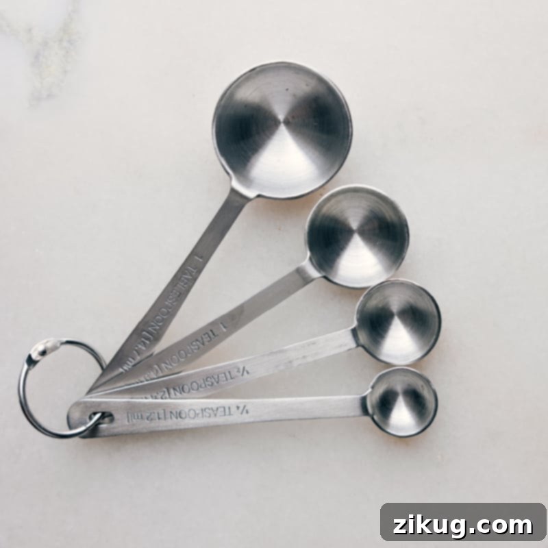 A set of metallic measuring spoons resting on a kitchen surface, ready for use.