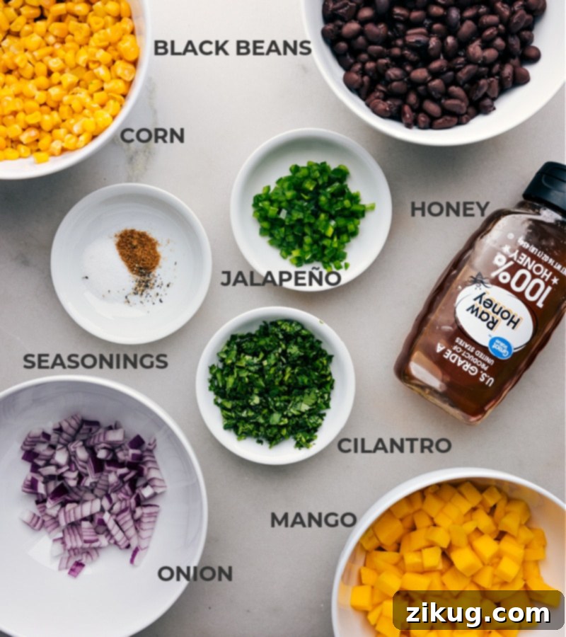 Ingredients in this recipe prepped and ready to go, including beans, corn, honey, jalapeño, seasonings, onion, and fruit.