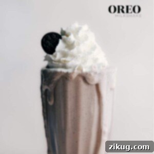 A tall, frosty glass of homemade Oreo Milkshake with whipped cream and crushed cookie topping.