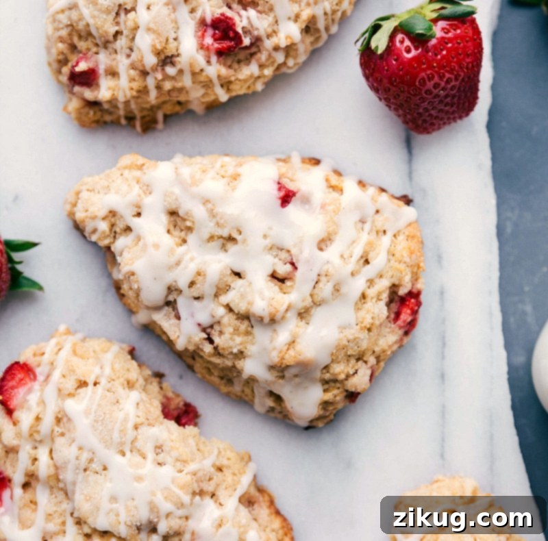 The finished strawberry scones generously drizzled with a smooth, sweet glaze, showcasing their golden-brown edges and soft texture, a delicious and delightful dessert ready to be served.