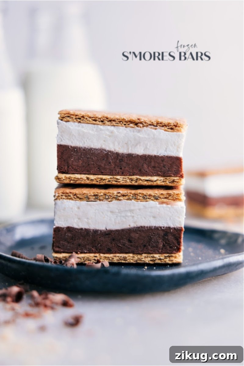 These delicious Frozen S'mores bars combine the rich and creamy flavors of chocolate pudding and whipped topping with the sweet, gooey goodness of marshmallow creme, all sandwiched between crispy honey graham crackers. A perfect no-bake treat for summer. Stacked Frozen S'mores Bars showcasing layers of chocolate pudding, marshmallow, and graham crackers