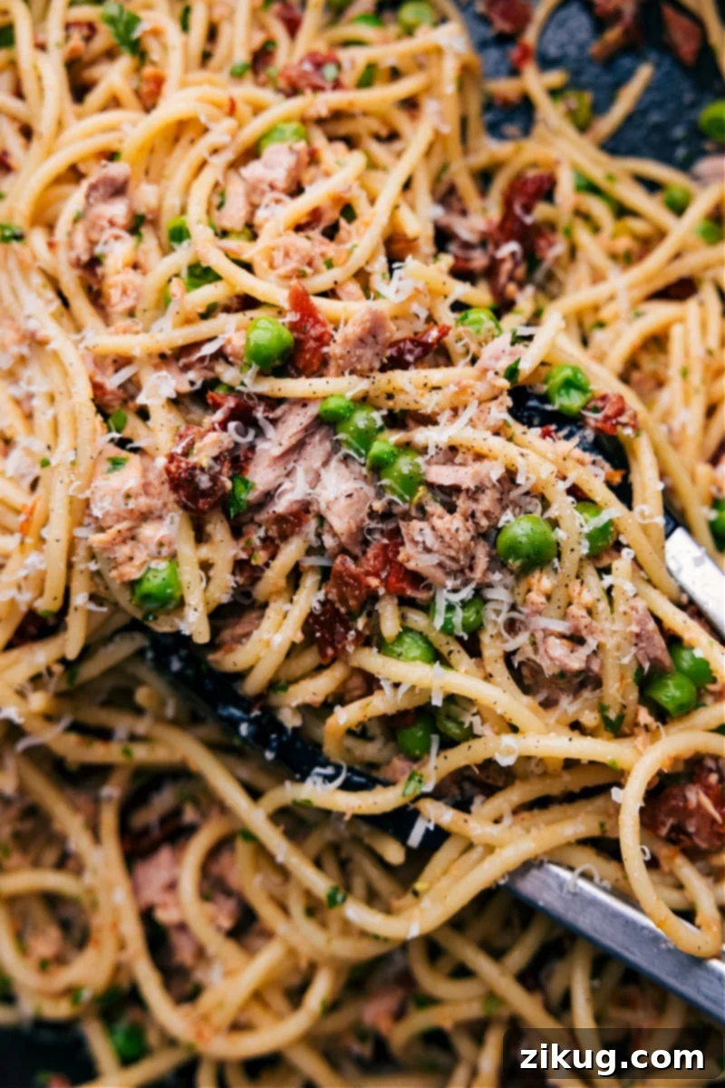 Ready-to-Enjoy Healthy Tuna Pasta A beautifully presented bowl of healthy tuna pasta, garnished with fresh herbs and grated Parmesan, ready to be enjoyed. The lighting highlights the vibrant colors of the ingredients, suggesting a fresh and appetizing meal.