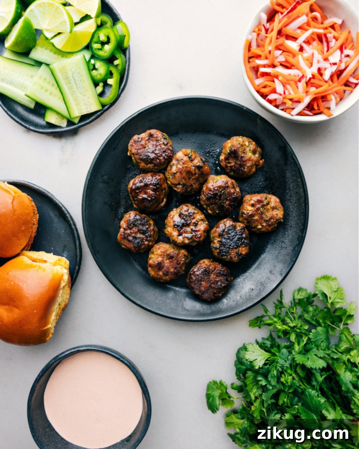 Perfectly baked pork banh mi meatballs presented amid an array of fresh ingredients, poised for slider assembly.