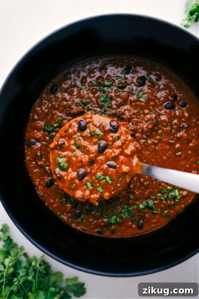 Delicious Pumpkin Chili Ready to Serve A close-up overhead shot of a pot of Pumpkin Chili with a ladle, showcasing its rich texture and color.