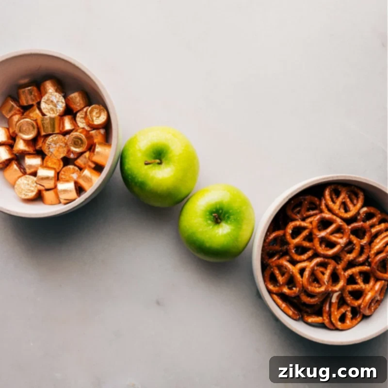 The 3-ingredients in this recipe set out for easy assembly. A green apple, unwrapped Rolos, and pretzel snaps are shown.