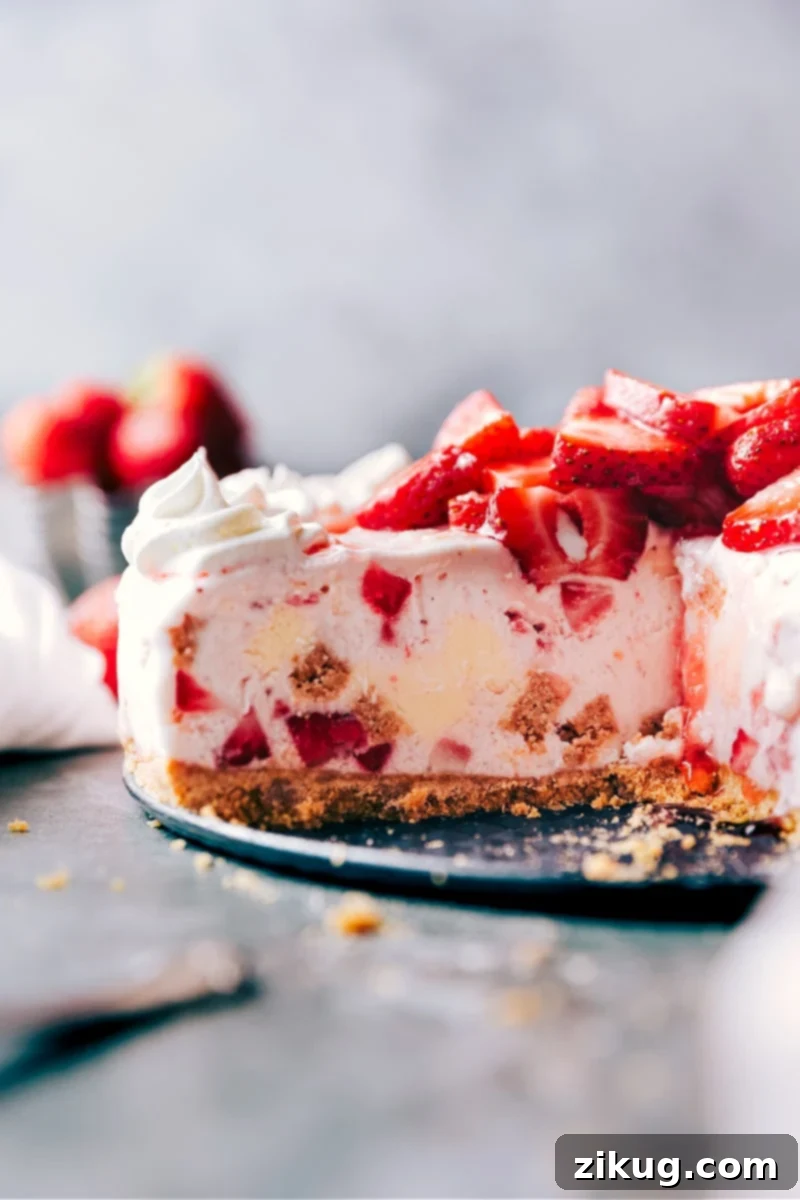 Simple, delicious, and easy Strawberry Cheesecake Ice Cream Cake with a buttery graham cracker crust and a two-ingredient strawberry cheesecake filling. Perfect no-bake dessert for summer parties! #dessert #icecreamcake #strawberry #cheesecake #nobake #easyrecipe Decadent Strawberry Cheesecake Ice Cream Cake on a serving platter, showcasing its creamy layers and graham cracker crust.