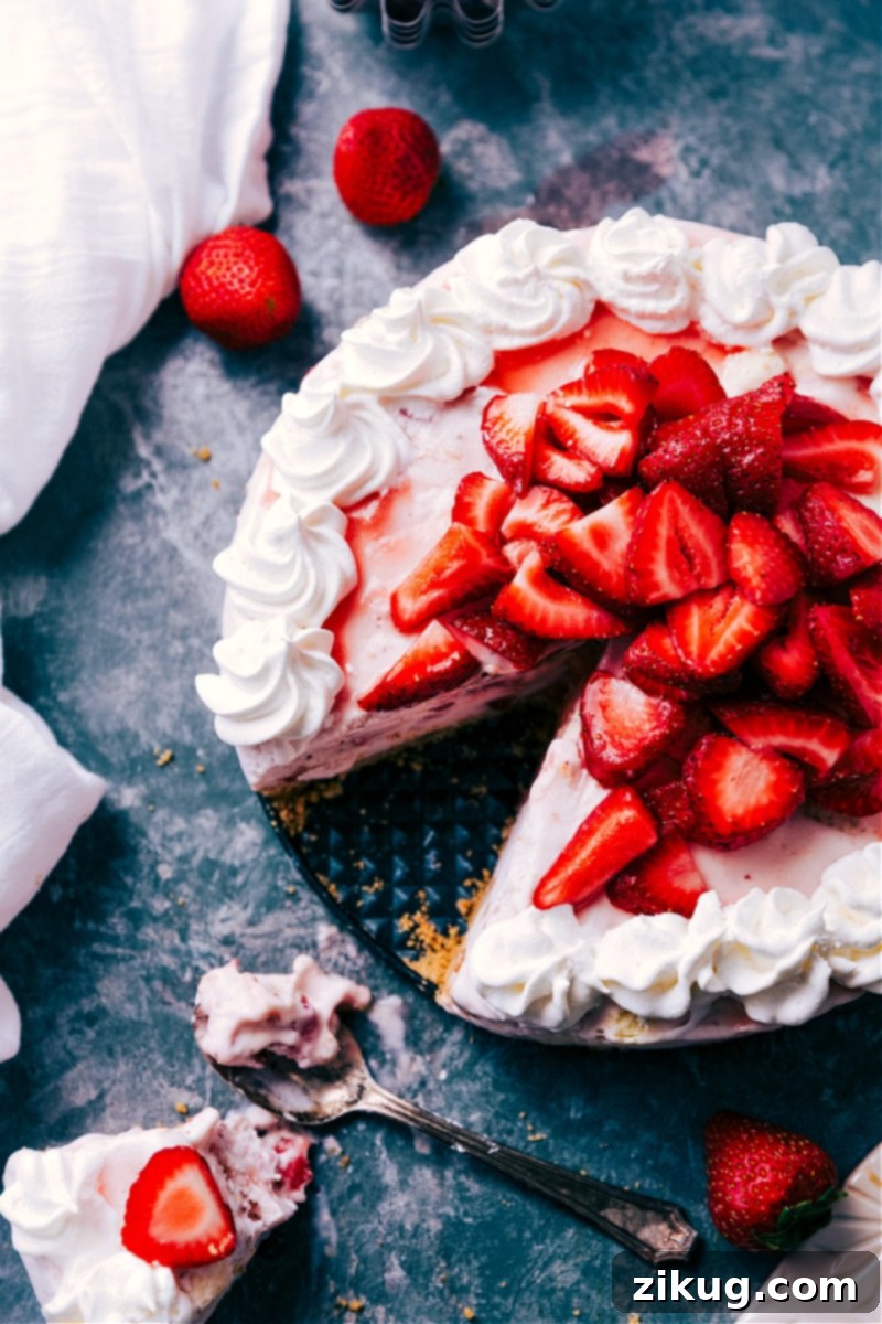 Gorgeous Strawberry Cheesecake Ice Cream Cake with its rich, buttery graham cracker crust and creamy two-ingredient strawberry cheesecake filling. An easy, no-bake masterpiece! #icecreamcake #strawberrydessert #cheesecake A perfectly sliced Strawberry Cheesecake Ice Cream Cake, garnished with fresh whipped cream and vibrant strawberries.