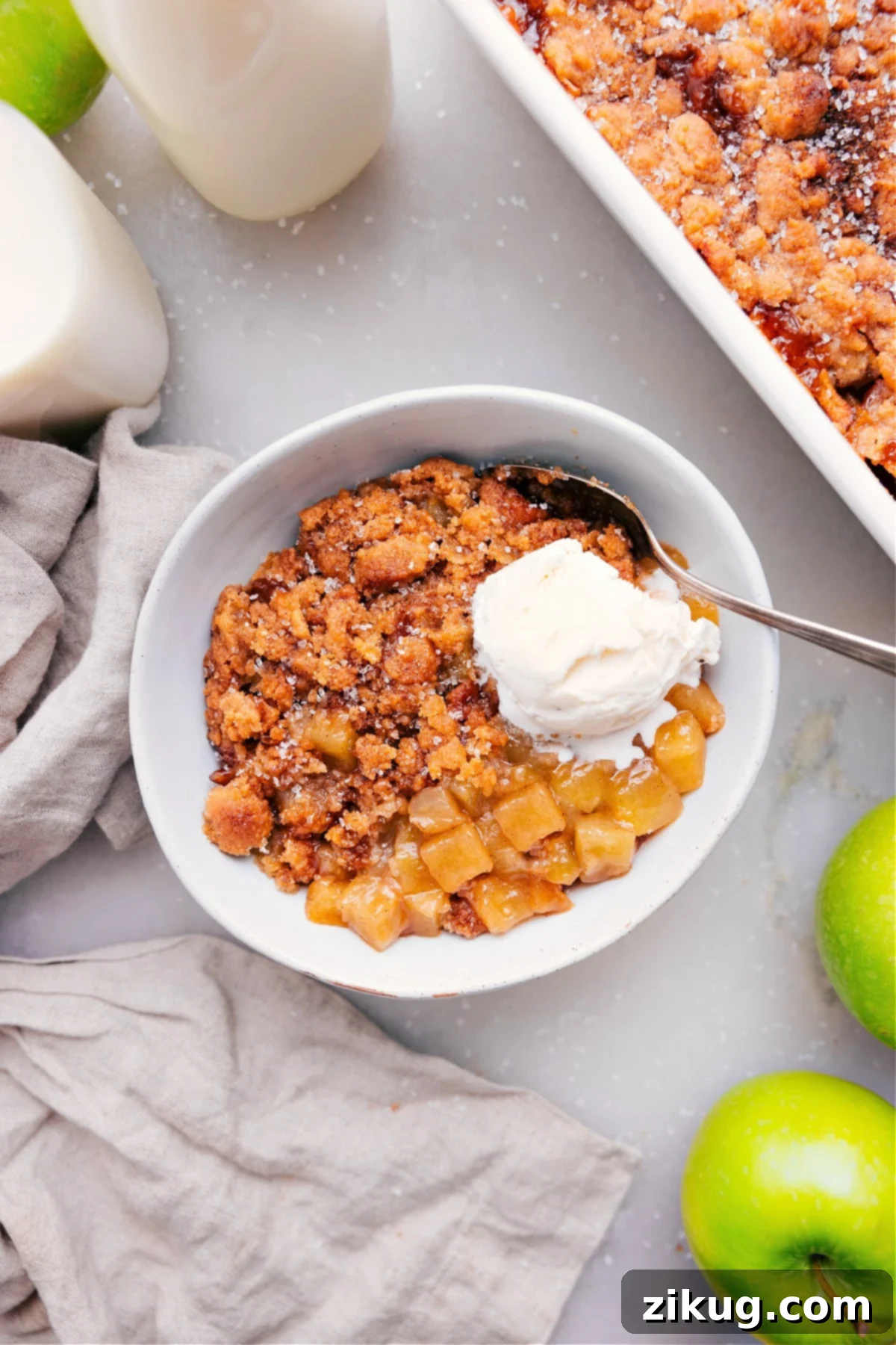 Delicious Warm Apple Cobbler Dessert with Ice Cream Warm apple cobbler with a scoop of melting vanilla ice cream in a white bowl, ready to be enjoyed.