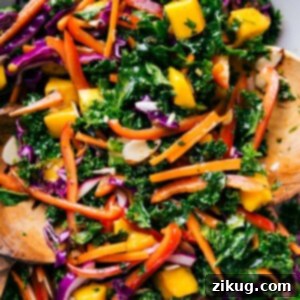 Elevated Kale Salad 3 Colorful bowl of the completed kale salad recipe, complete with wooden serving spoons.
