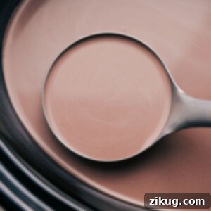 Creamy Slow Cooker Hot Chocolate 2 A spoonful of the warm beverage, poised and ready to be poured into a waiting mug.