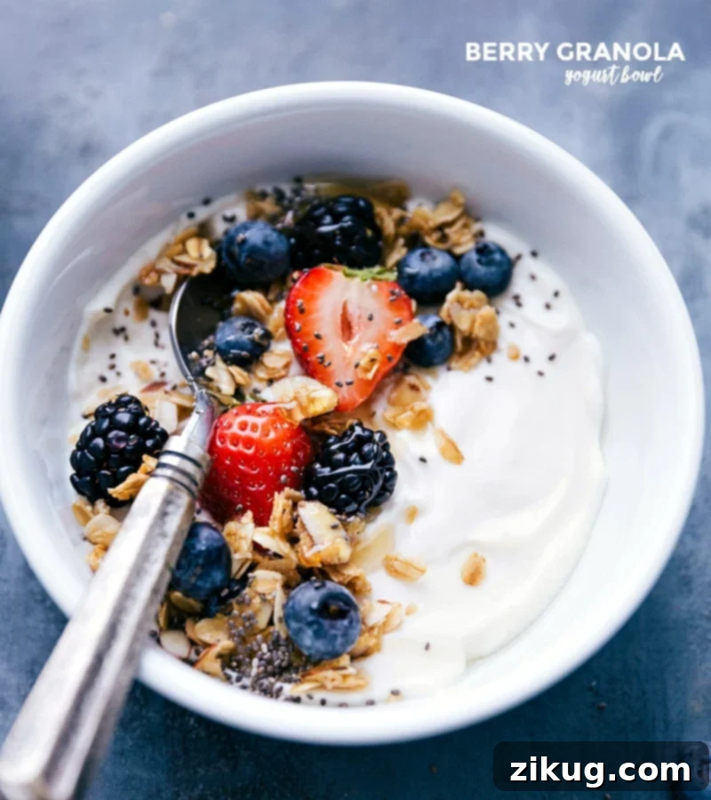 Berry-granola yogurt bowl topped with fresh berries and granola, accompanied by a spoon, prepared for a delightful meal. The image highlights juicy blueberries, raspberries, and crunchy granola.