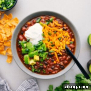 A vibrant bowl of Easy Taco Soup, brimming with seasoned beef, beans, corn, and chili, beautifully garnished with fresh cilantro, a dollop of sour cream, and shredded Cheddar cheese, promising a burst of flavor and texture with every spoonful.